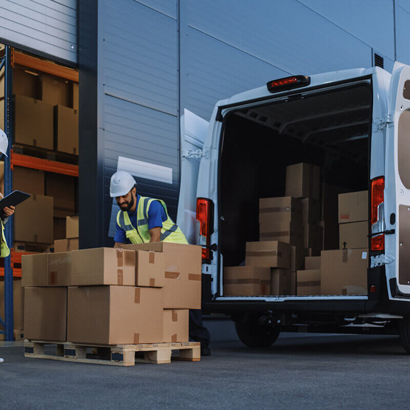 Workers taking goods from the back of a van and putting into a pallet