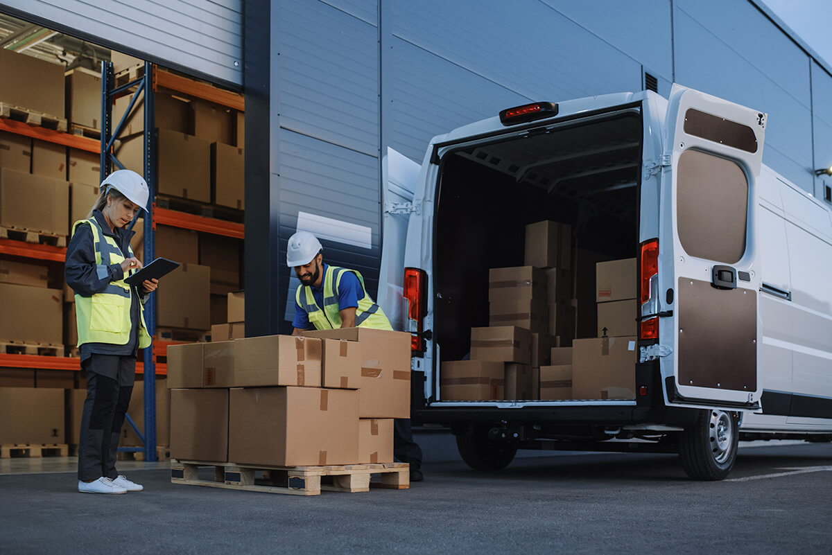 Workers taking goods from the back of a van and putting into a pallet