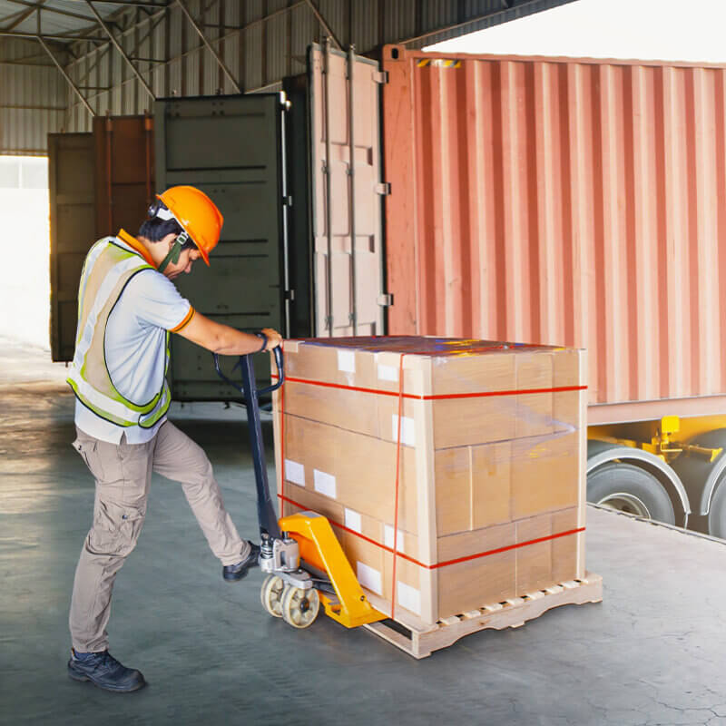 Worker unloading a pallet of goods from truck container