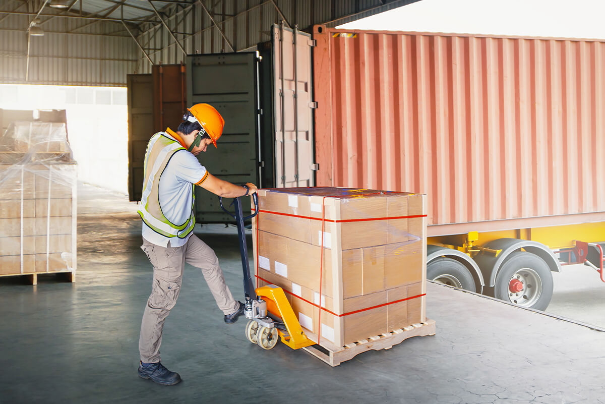 Worker unloading a pallet of goods from truck container