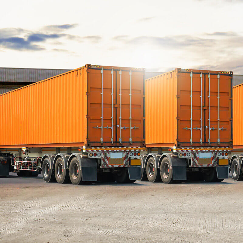 trucks with orange colored containers are positioned at the dock